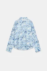 Camisa de manga larga con cuello solapa y cierre frontal de botones, confeccionada en tejido combinado semitransparente con estampado floral en tonos azules y blancos.
