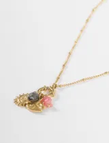 Collar de cadena fina plateada con un conjunto de dijes colgantes, incluyendo un sol, una luna y elementos decorativos con detalles en color rosado.