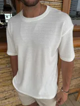 Remera de corte oversize color blanco, confeccionada en tejido de punto con textura sutil, cuello redondo y mangas cortas.