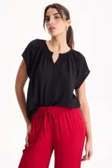 Blusa negra de manga corta, confeccionada en tela crepé, con detalle de fruncido en el escote redondo y pequeña abertura frontal en V.