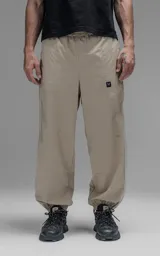 Pantalón deportivo de microfibra color beige, con corte regular y diseño de inspiración vintage. Presenta vivos laterales a contratono, cintura elástica y puños elásticos en los tobillos.