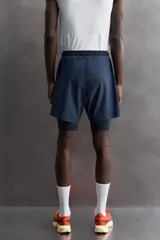 Shorts de entrenamiento azul marino con calza interior negra. Cintura elástica ajustable con cordón, bolsillos laterales con cierre y aberturas laterales en el bajo.