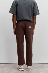 Pantalon de corte recto en color marron, confeccionado en tela resistente, con bolsillos laterales tipo parche y cierre frontal.