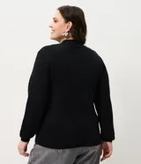 Buzo de punto negro con textura geométrica tipo colmena, cuello alto y mangas largas con puños ajustados.