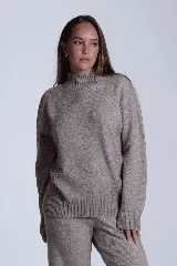 Sweater color beige de tejido de punto con cuello alto y mangas largas. Presenta detalles de ochos en diagonal en los laterales.