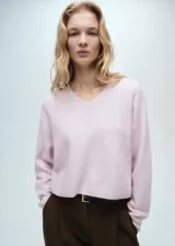 Jersey de punto color rosado con cuello en V, manga larga y diseño recto con terminaciones acanaladas.