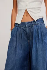 Pantalón de denim celeste de tiro bajo, pierna muy ancha y diseño sastrero con tablas al frente. Cuenta con cintura fruncida en la espalda, bolsillos y cierre frontal con cremallera y gancho.