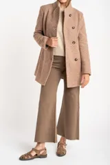 Tapado de poliéster con textura en color beige, de calce al cuerpo. Cuenta con cuello alto, cierre frontal de botones oscuros y bolsillos laterales.