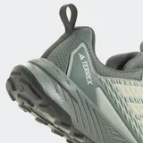 Championes de trail running Adidas Terrex Tracefinder 2, color verde grisáceo con detalles en verde menta y blanco. Presentan un empeine de malla con refuerzos sintéticos, amortiguación LIGHTMOTION y suela Traxion.