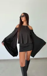 Vestido corto negro con diseño de hombros descubiertos y mangas largas acampanadas de gran amplitud. Presenta un corte ajustado en la parte inferior y un estilo fluido en la parte superior.