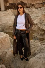 Pantalón de cuero negro con corte de jean y tiro medio, presenta apliques decorativos de rosetas en la parte delantera.