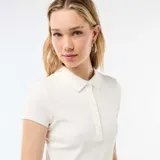 Remera de punto canalé color blanco, con cuello polo y cierre frontal de botones, manga corta y diseño ajustado.