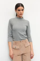 Polera de algodón color blanco, con cuello alto y mangas tres cuartos. Presenta un diseño ajustado al cuerpo con costuras decorativas en las sisas.