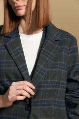 Blazer de corte sastrero con estampado de cuadros en tonos beige, marrones y rojizos. Presenta solapas clásicas, cierre frontal con un botón y bolsillos laterales con solapa.