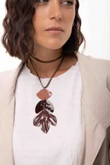 Collar de diseño artesanal con tres medallones texturados en tonos tierra, unidos por arandelas metálicas. Cuenta con un tiento sintético regulable que permite ajustar el largo y la posición de las tiras.