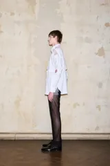 Pantalón negro de tiro alto y pierna recta, con laterales de malla transparente y cierre frontal.