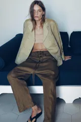 Pantalón tipo baggy de tiro bajo, confeccionado en mezcla de lino. Presenta cintura elástica con cordón ajustable, cierre frontal con botones y falsos bolsillos de vivo en los laterales.