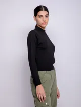 Polera negra de tejido de punto, manga larga y cuello alto.