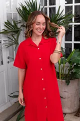 Vestido camisero de muselina color negro, de largo midi, con cuello clásico, manga corta y cierre frontal con botones.