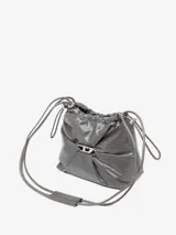 Bolso tipo cubo Diesel Scrunch-D, color gris oscuro, confeccionado en cuero brillante con efecto arrugado. Presenta logo metálico "D" en el frente, cierre con cordones ajustables, correa de hombro extraíble y múltiples bolsillos internos.