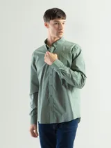 Camisa de manga larga confeccionada en algodón, con cuello abotonado y cierre frontal de botones. Presenta un diseño clásico y versátil con un pequeño logo bordado en el pecho.