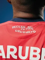 Camiseta de fútbol Umbro de arquero del Club Nacional de Football, modelo Oficial 2025. Diseño con patrón gráfico en tonos azules y detalles en rojo en cuello y mangas. Incluye logo de Umbro, escudo del club y sponsor Antel en el frente.