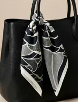 Pañuelo cuadrado de seda con estampado floral en tonos verde, blanco y negro.