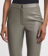 Pantalón tipo legging de mujer, color crema claro, confeccionado en poliuretano (PU) con un diseño liso. Presenta un cierre frontal con botones visibles en la cintura.