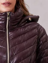 Campera puffer de acabado satinado en color marrón oscuro. Presenta un diseño capitoneado con líneas en V, cierre frontal metálico, capucha fija y puños internos de tejido elastizado con abertura para el pulgar. Incluye bolsillos laterales con cierre invisible y logo metálico en la manga.