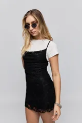 Vestido corto de encaje negro con breteles finos y corte ajustado al cuerpo.