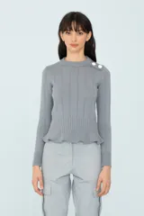 Sweater gris de punto con calce al cuerpo, volado en el ruedo y botones decorativos en el hombro.
