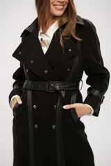 Tapado negro de corte cruzado con detalles en cuero sintético en solapas, puños y cierre frontal. Incluye cinturón ajustable con hebilla y botones metálicos.