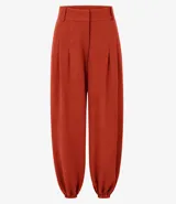 Pantalón balloon de piqué color terracota, con cintura estructurada, pinzas delanteras, pasacintos, piernas amplias y dobladillos elásticos.