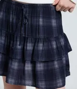 Short pollera de tiro medio con estampado de cuadros escoceses en tonos azul y gris. Presenta diseño de volados sobrepuestos y cintura con lazo ajustable.