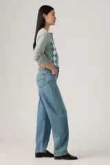 Pantalón de jean de corte baggy con diseño barrel, tiro medio y lavado azul claro con efecto desgastado. Presenta costuras laterales curvadas que definen su silueta amplia y relajada.