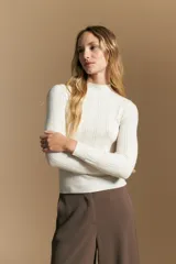 Polera de punto acanalado color gris, con cuello alto y mangas largas, de calce ajustado al cuerpo.