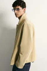 Cazadora regular fit de cuero con acabado de ante en color beige, con cuello solapa, bolsillos de plastrón en la cadera y cierre frontal de cremallera oculta por solapa con botones a presión.