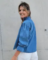 Blusa de algodón con cuello mao y volados, mangas largas con puños elásticos y corte holgado.