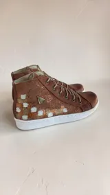 Botas de media caña de cuero color terra con brillo jaspeado en tono cobre, con detalles de arte pintado a mano en el talón, suela de goma blanca y cordones beige.