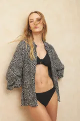 Parte inferior de bikini negra, estilo clásico, con textura acanalada y detalle de aro metálico en el centro frontal.