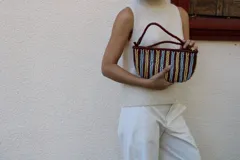 Cartera tipo sobre confeccionada en cuero trenzado a mano, con diseño de rayas verticales en tonos negro y natural.