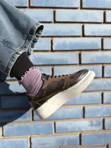 Zapatillas deportivas de cuero color peltre, con cordones negros y suela de goma blanca.