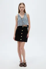 Falda mini de denim negro con corte recto, pespuntes en contraste y cierre frontal de botones dorados en forma de corazón.