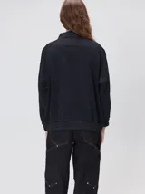 Buzo verde militar de algodón suave, de calce oversize, con cuello alto y cierre frontal parcial metalizado. Cuenta con bolsillos laterales con cierre y puños y ruedo elastizados.