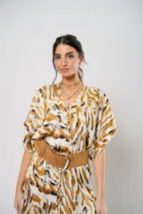 Vestido largo con estampado animal print en tonos camel, blanco y negro. Tiene escote en V, mangas cortas tipo murciélago y tajo frontal. Incluye cinturón ancho de cuero color camel.