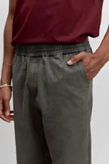 Pantalon de corte recto en color verde oliva, confeccionado en tejido de algodón con acabado ligeramente desgastado, cuenta con bolsillos laterales y cierre frontal.