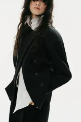 Blazer de cuello redondo y manga larga con volumen, color negro, de cierre cruzado con botones.