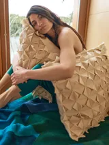 Almohadón cuadrado de lana color beige, con diseño geométrico en relieve. Relleno con funda de algodón, guata y restos textiles.