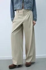 Pantalón de tiro medio con diseño de pierna ancha y pinzas frontales. Cuenta con bolsillos laterales ocultos, falsos bolsillos traseros de vivo, trabillas en la cintura y cierre frontal con cremallera y ganchos metálicos.