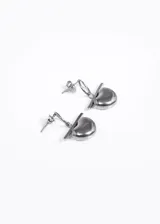 Par de aros colgantes de acero quirúrgico plateado, con forma de corazón atravesado por una barra horizontal.